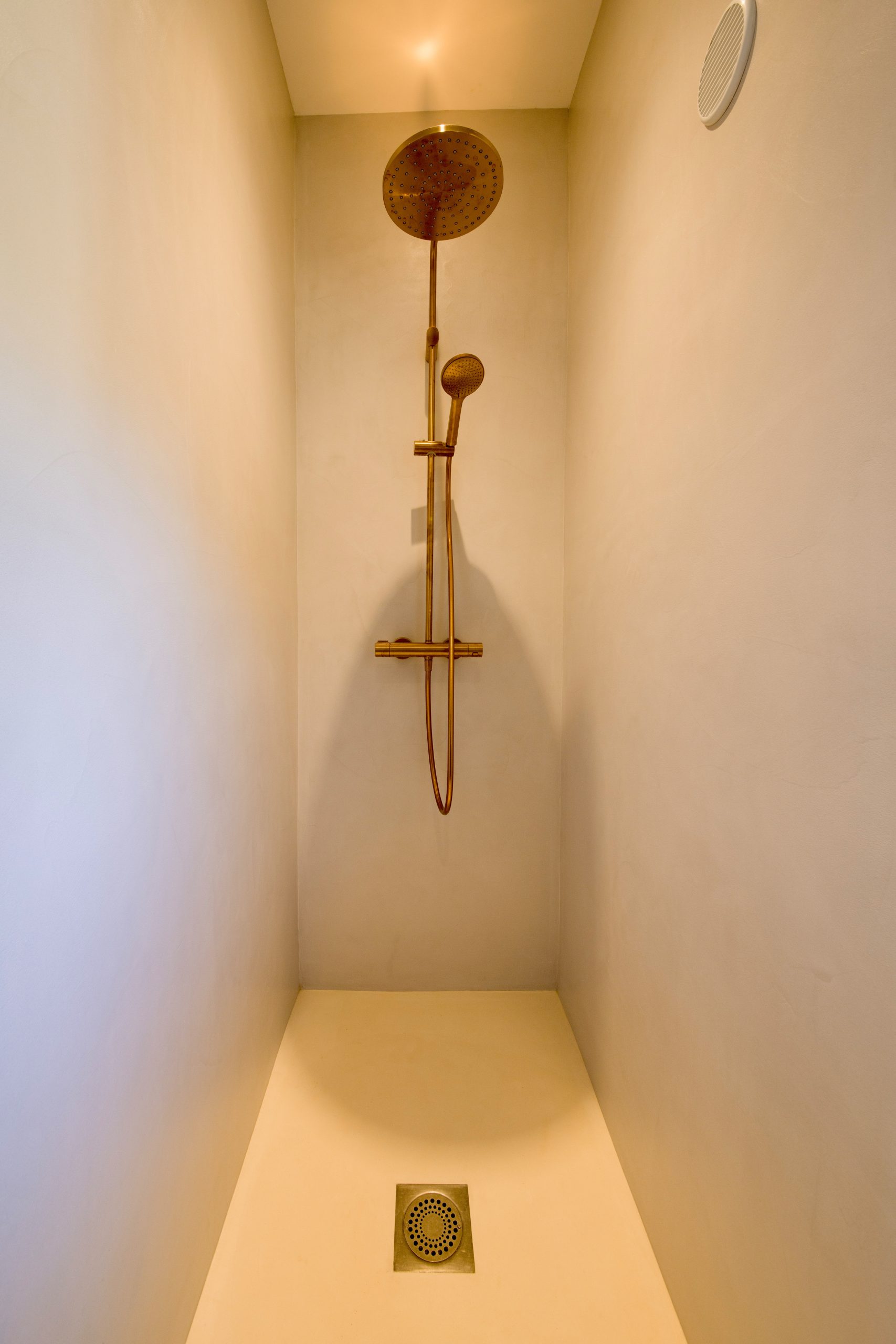 Douche en béton ciré beige avec robinetterie noire réalisée à Toulon par Clavel Rénovation.