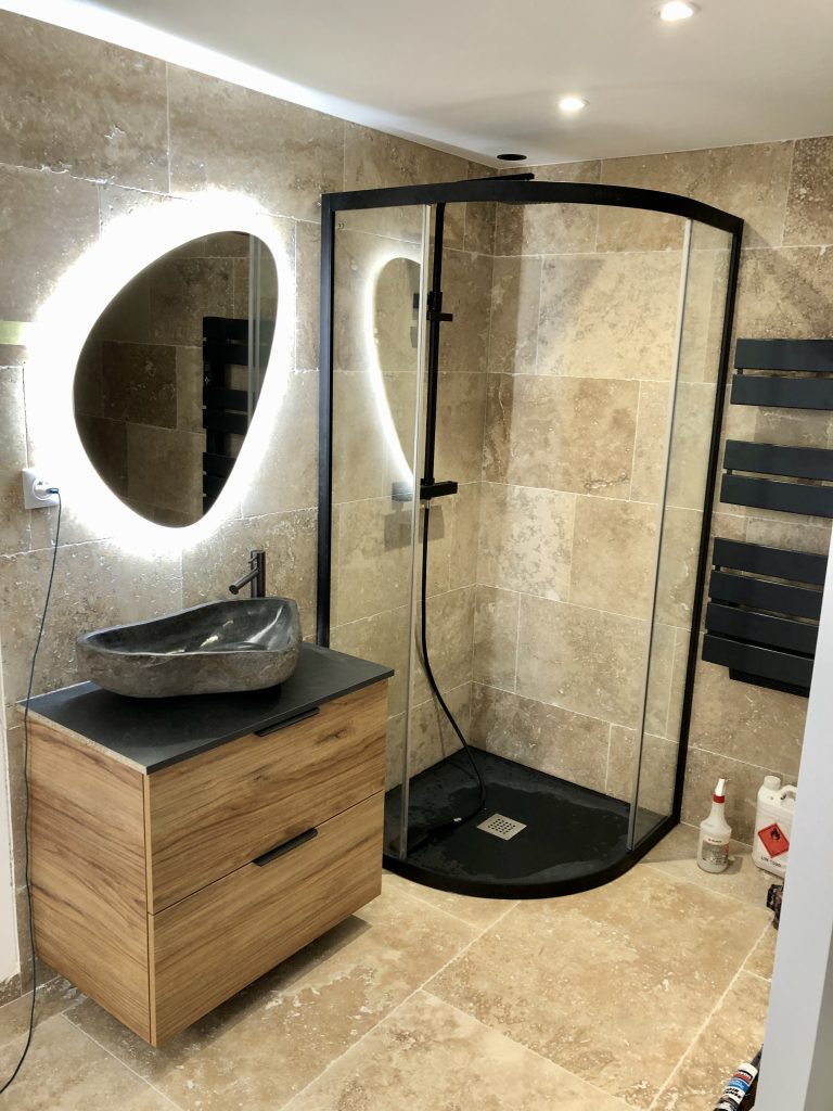 Rénovation de salle de bain travertin à Toulon avec douche quart de rond noir et meuble bois