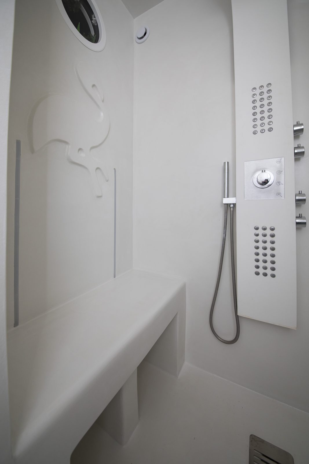 Banc maçonné et niche en béton ciré blanc dans une douche à l'italienne, presqu'île de Giens