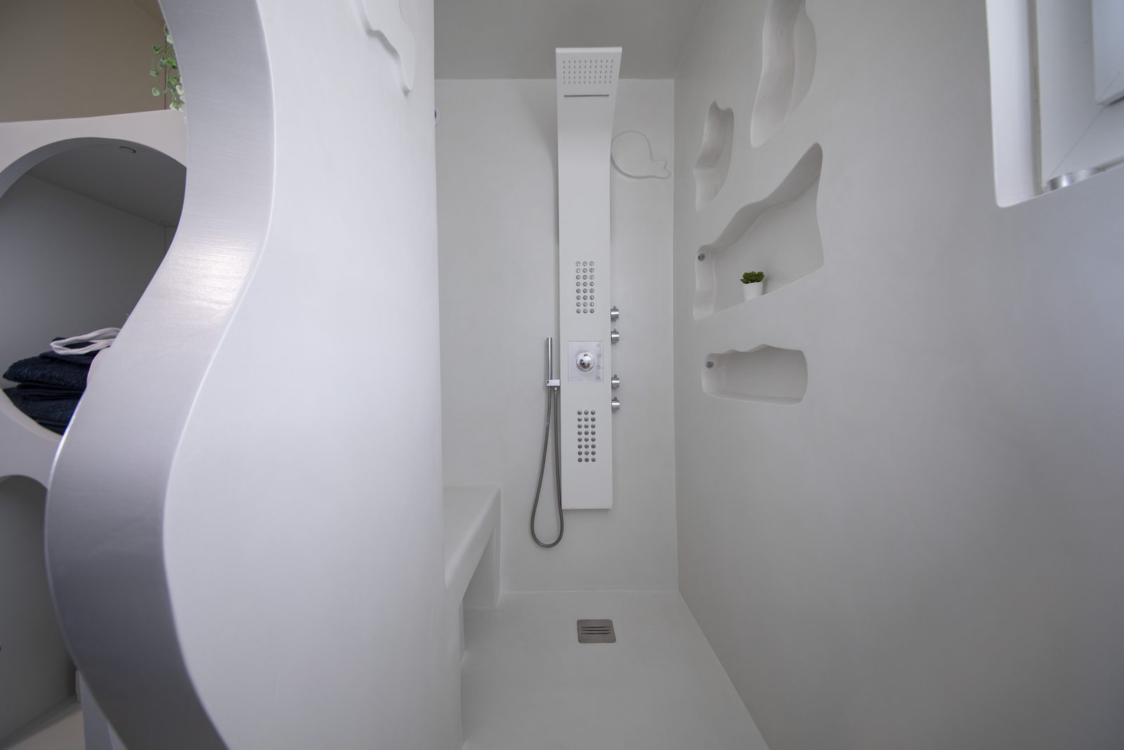 Douche à l'italienne en béton ciré blanc avec cloison sculptée sur mesure, réalisée à Giens (Hyères)